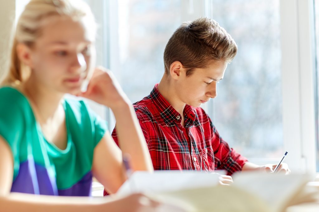 group of students with books writing school test